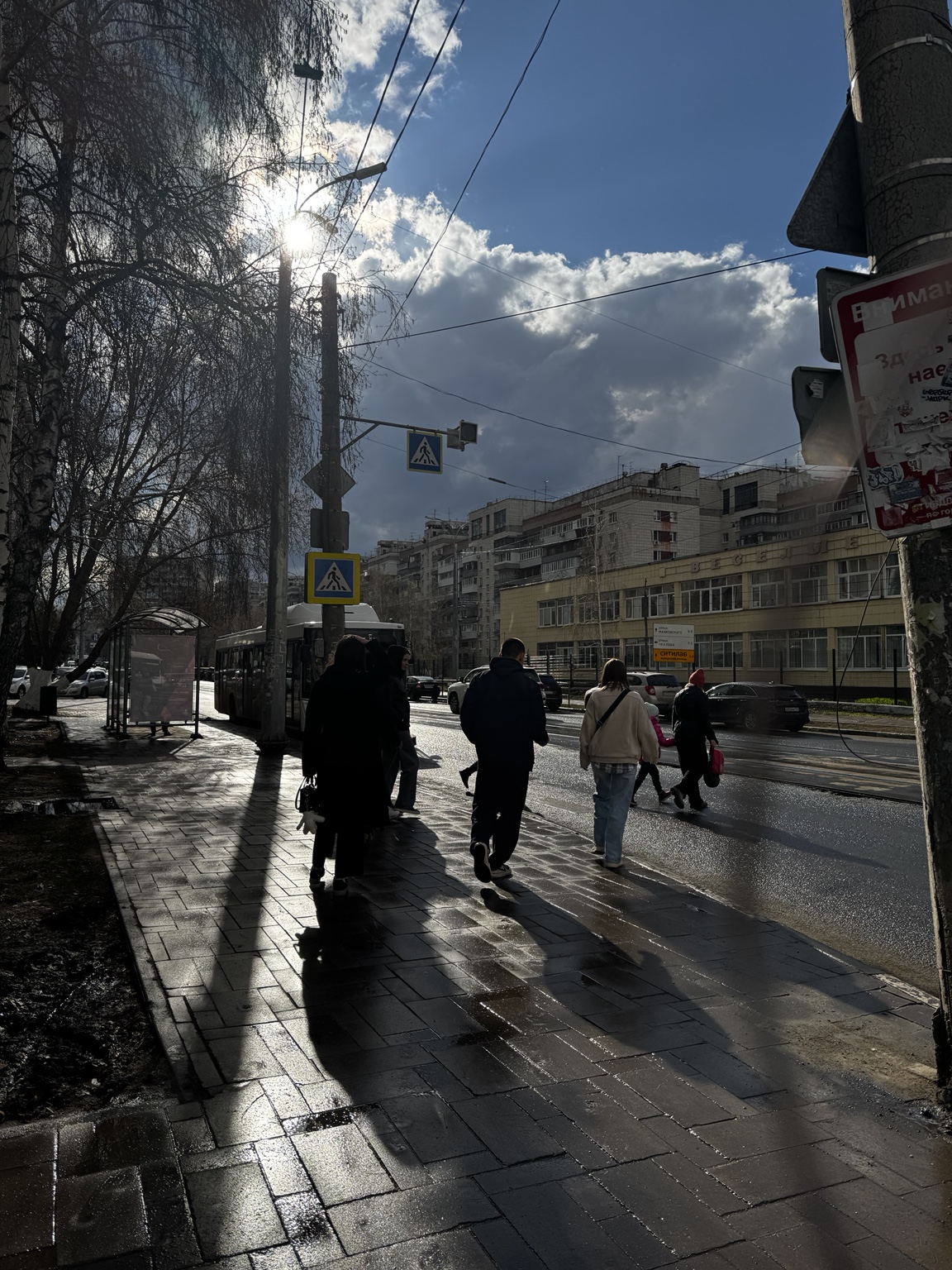 People crossing a wet city street in strong sunlight