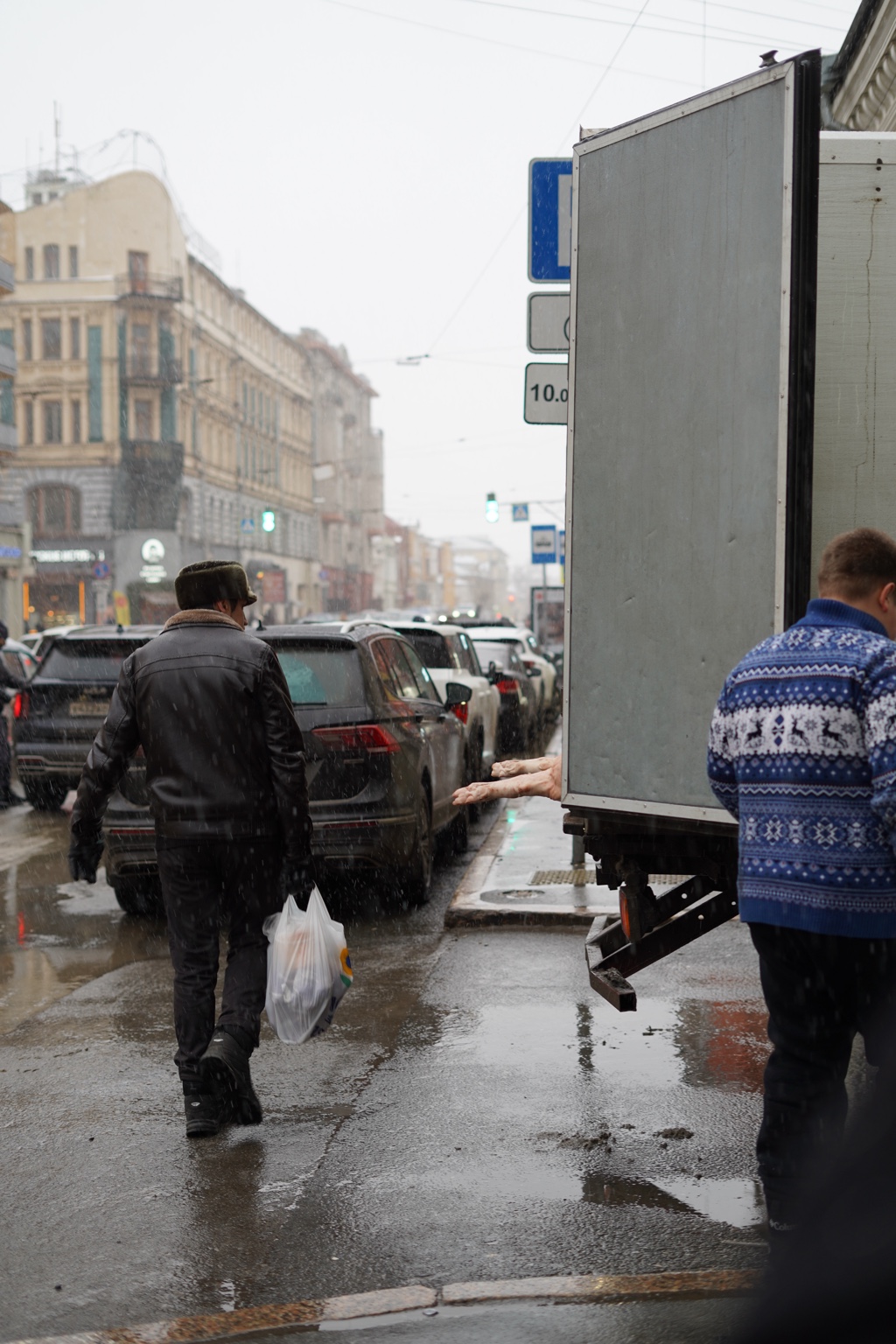 People walking beside a truck on a rainy city street
