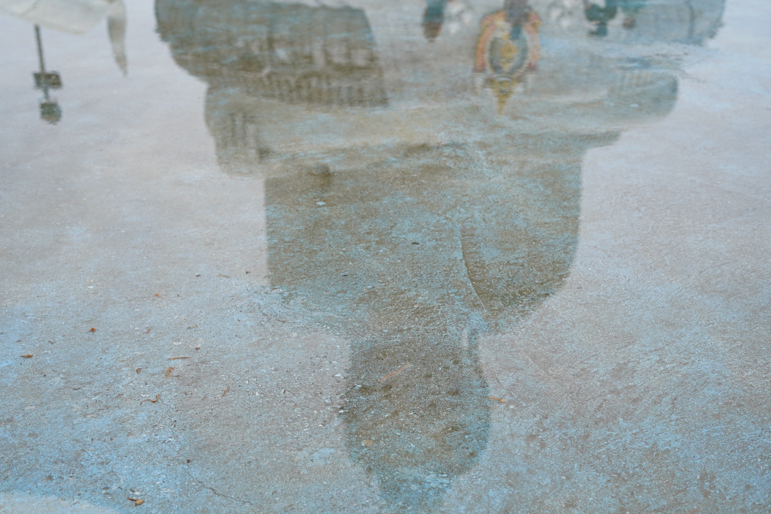 A soft reflection in blue-toned pavement