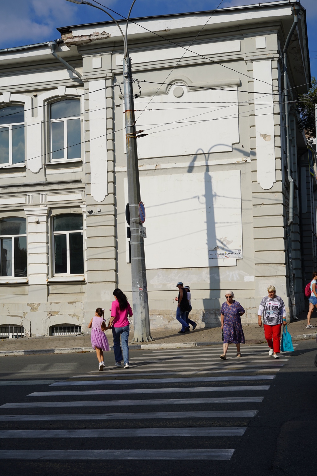 People crossing in front of a pale city building