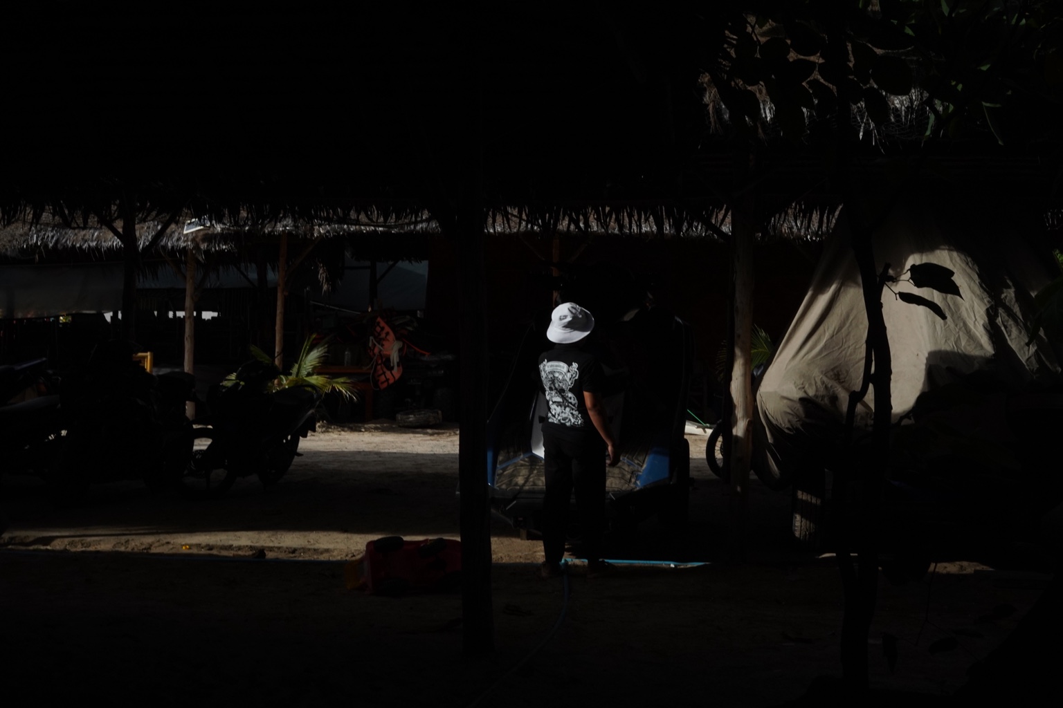 A figure in a white hat standing in deep shadow
