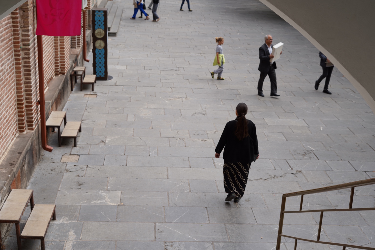 People crossing a stone courtyard viewed from above