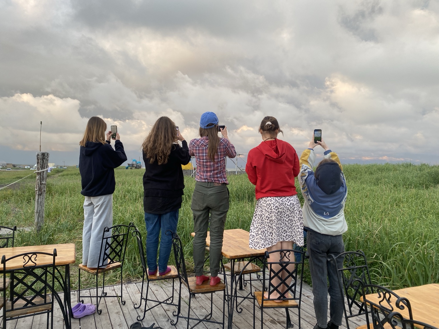 People standing on chairs photographing dramatic clouds