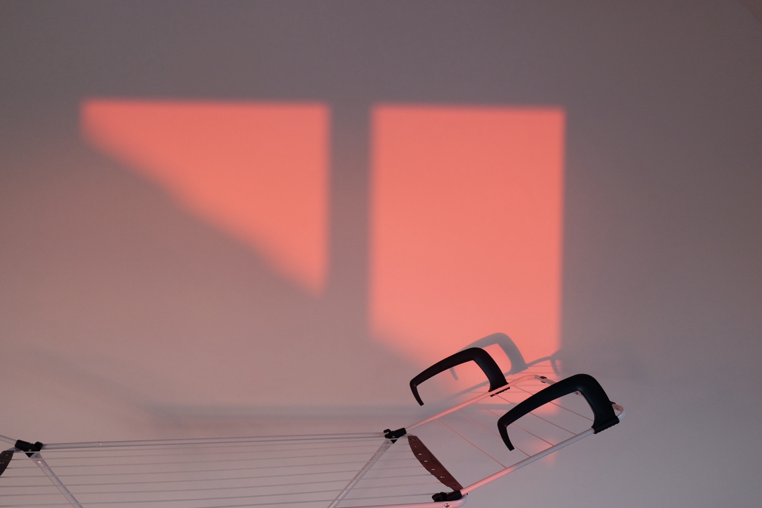 Pink window light and chair shadows on a wall
