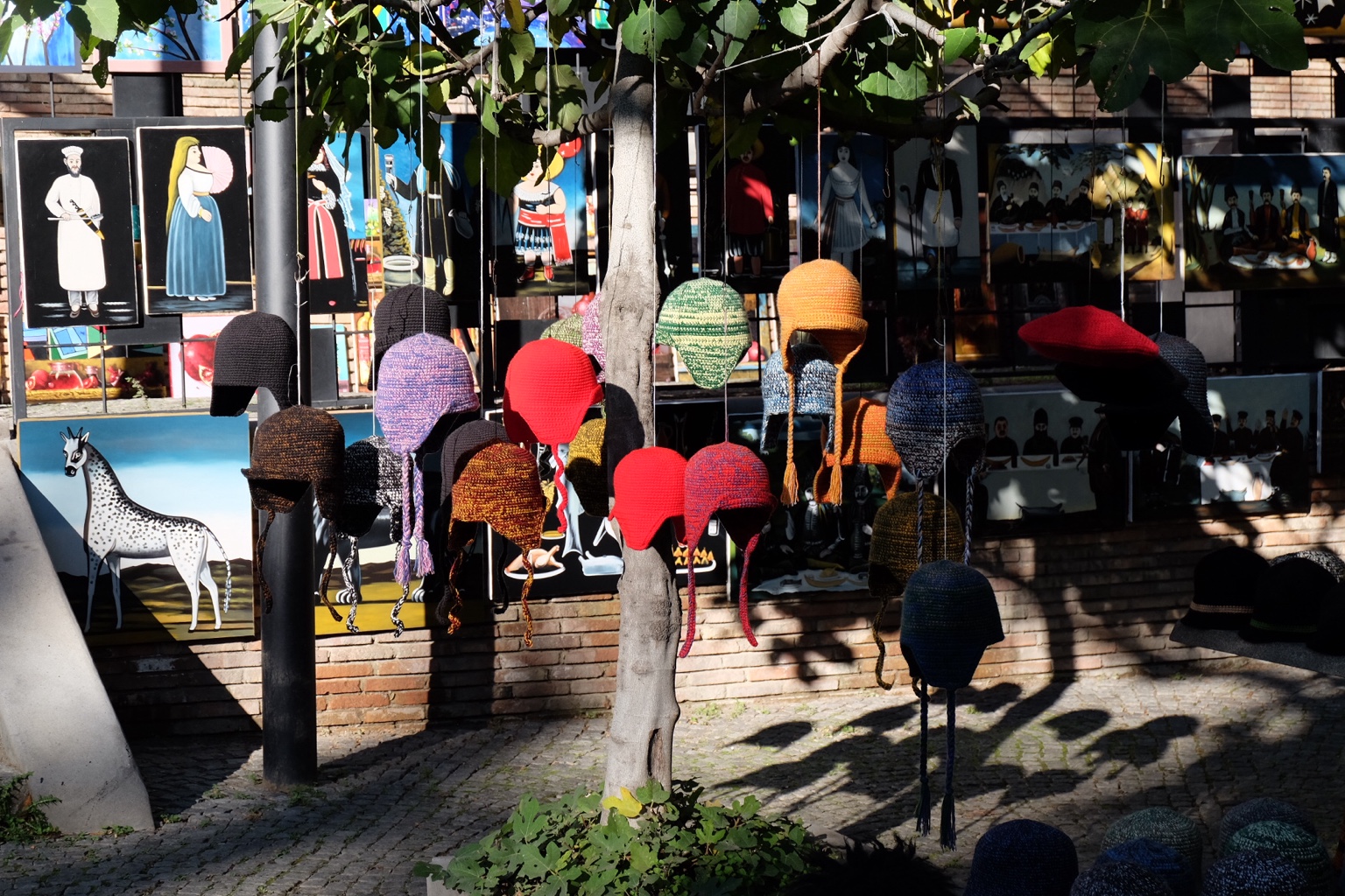 Colorful knitted hats hanging in front of paintings