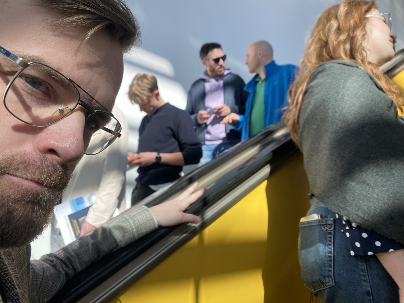 Close face and passengers on an escalator in hard sunlight