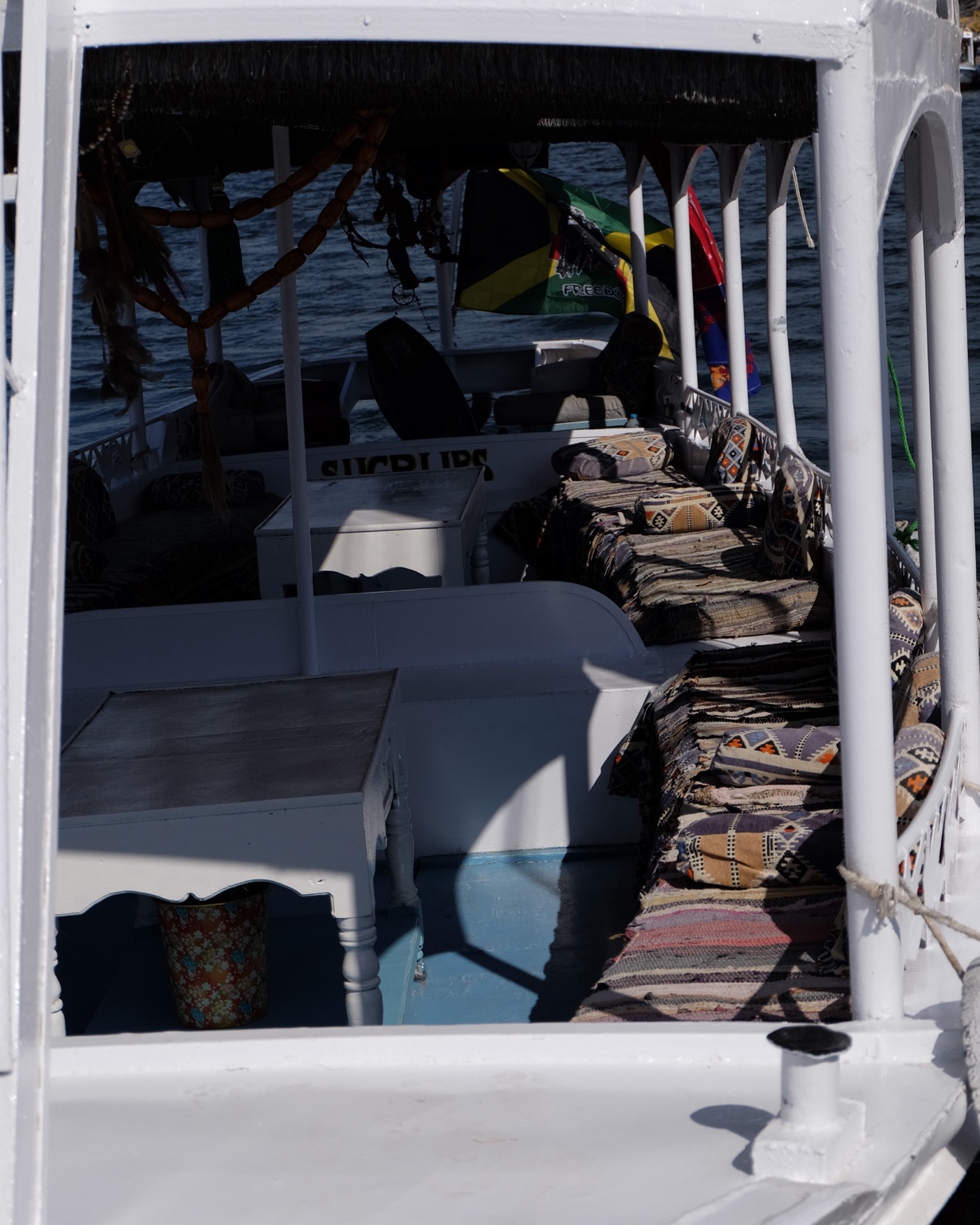 Interior of a small white boat with patterned cushions and deep shadows