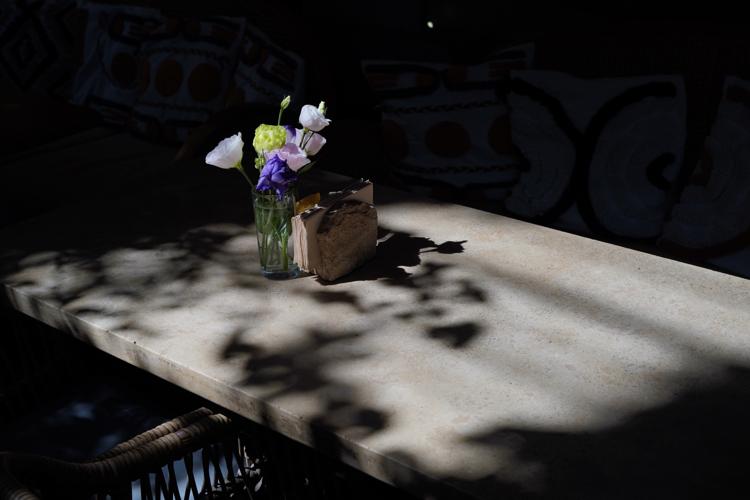 Flowers in a glass vase on a table with strong shadows